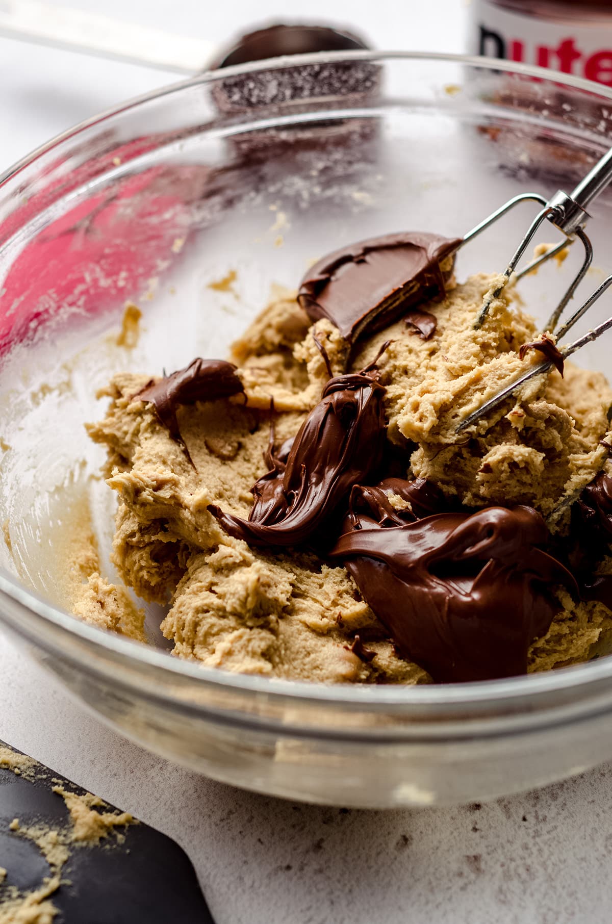 cookie dough being swirled with nutella in a bowl with beaters