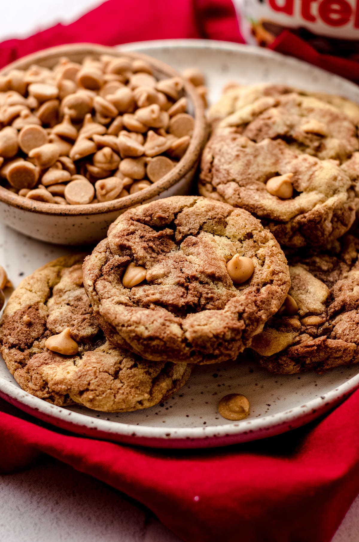 nutella peanut butter chip cookies on a plate with a bowl of peanut butter chips