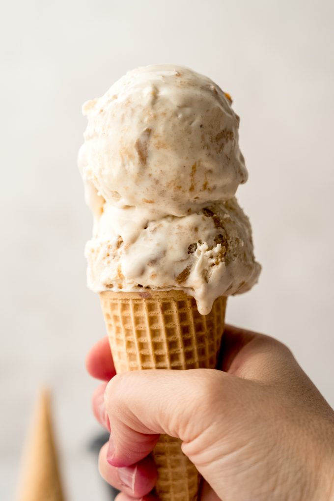 Someone's hand holding a cone of peanut butter ripple ice cream.