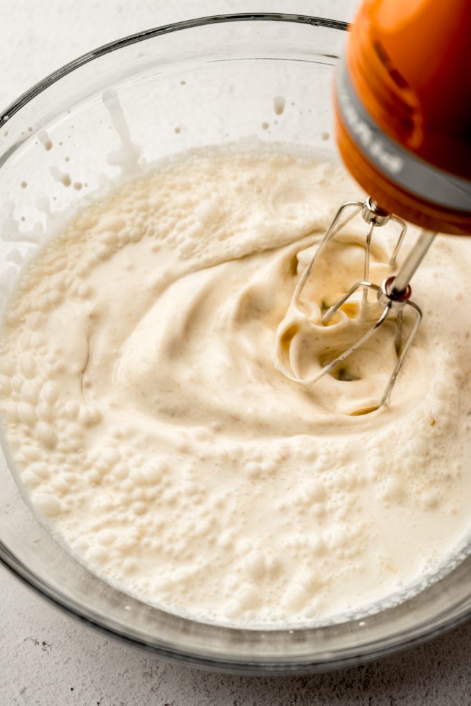 A bowl of the base ingredients for peanut butter ripple being whipped with a handheld mixer.