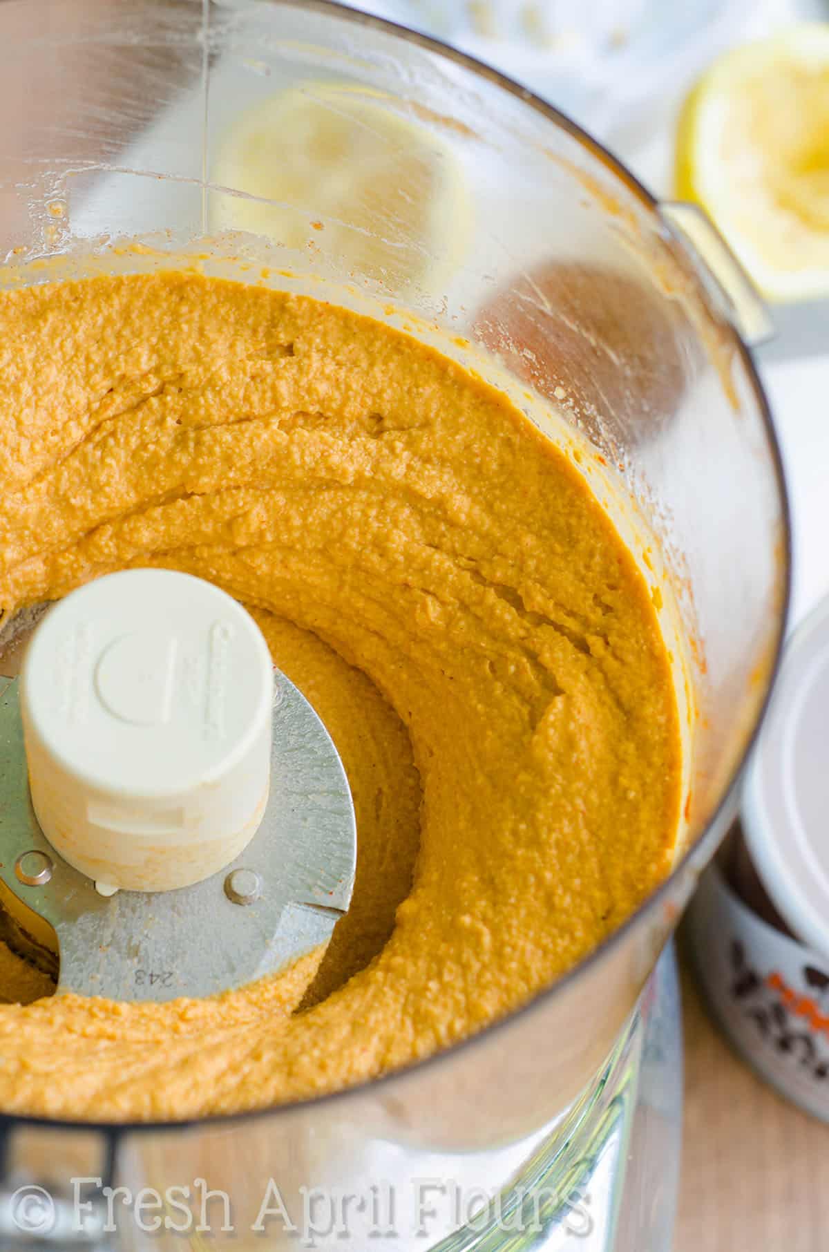 Creamy buffalo hummus in a food processor.