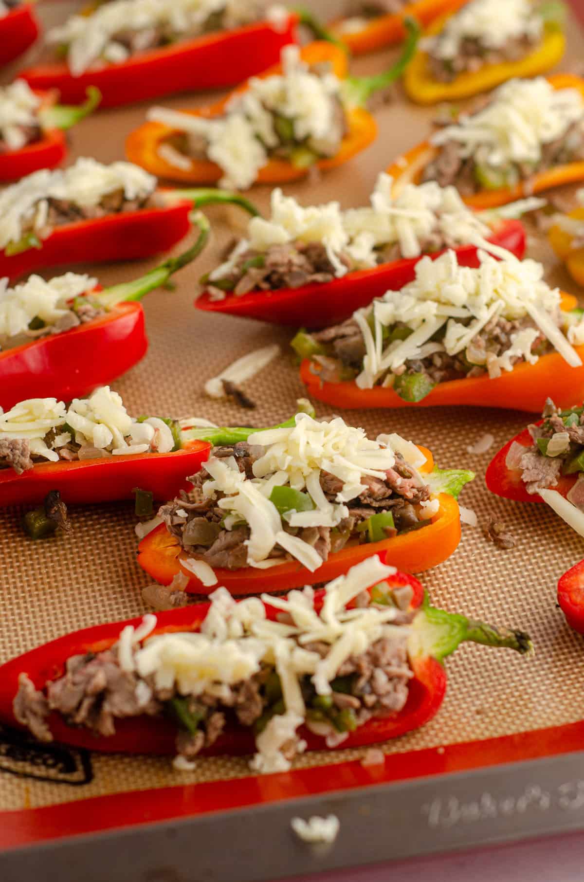 mini bell peppers on a baking sheet stuffed with filling and ready to bake