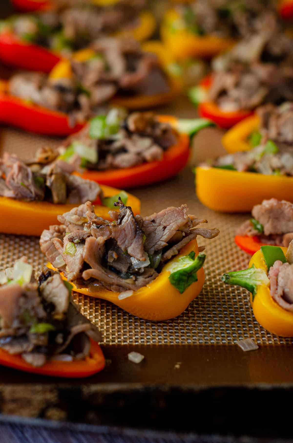 mini bell peppers on a baking sheet stuffed with filling and ready to bake