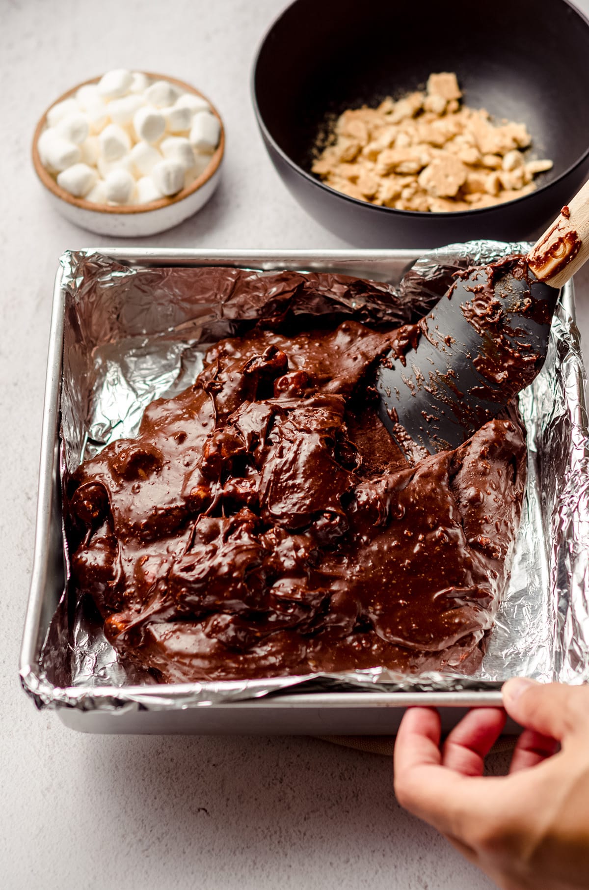 spreading s'mores fudge into a baking pan