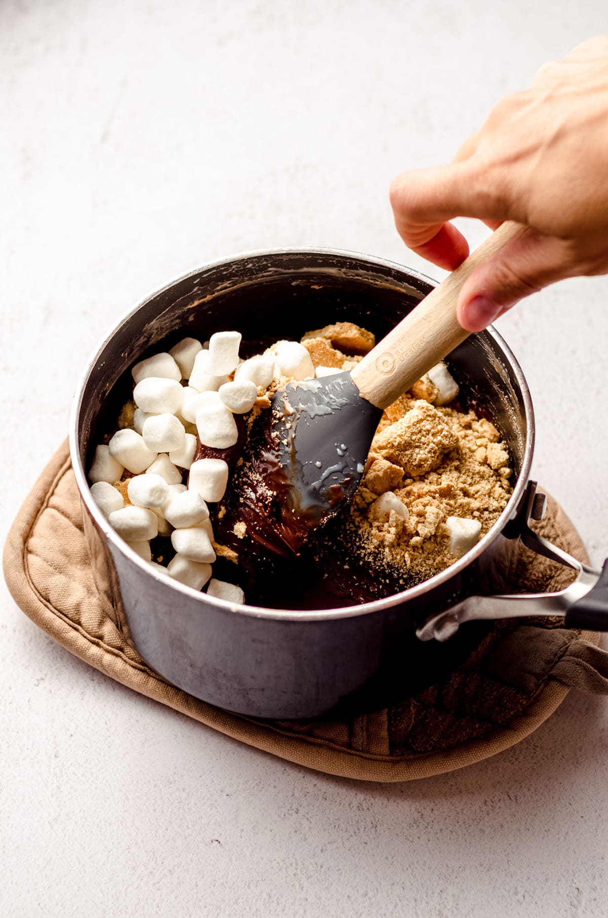 stirring ingredients for s'mores fudge in a saucepan