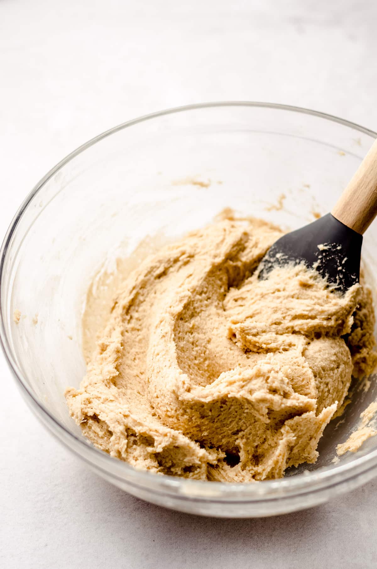 snickerdoodle cookie dough in a glass bowl with a spatula