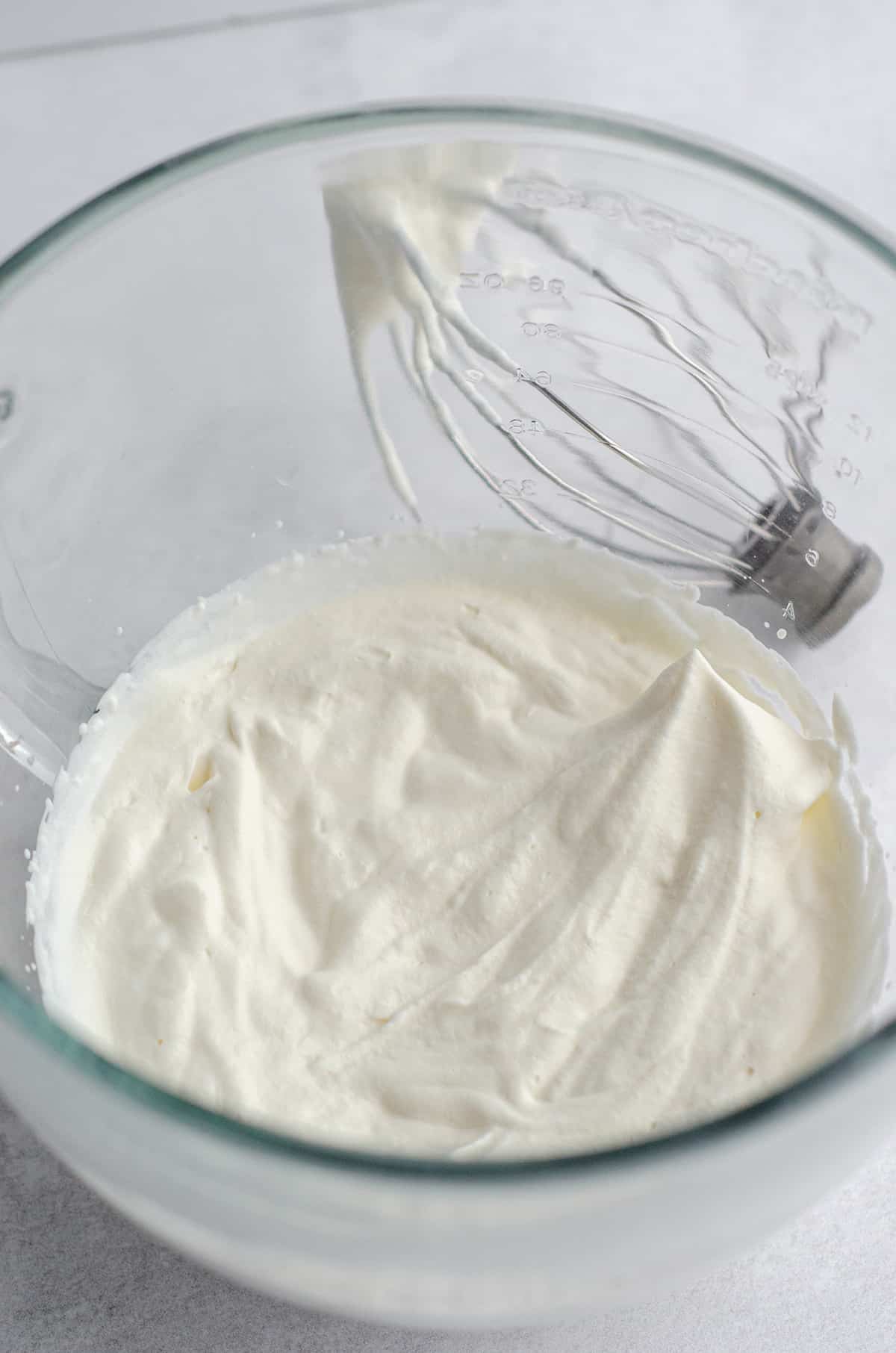 stiff peaks in homemade whipped cream in a glass bowl 