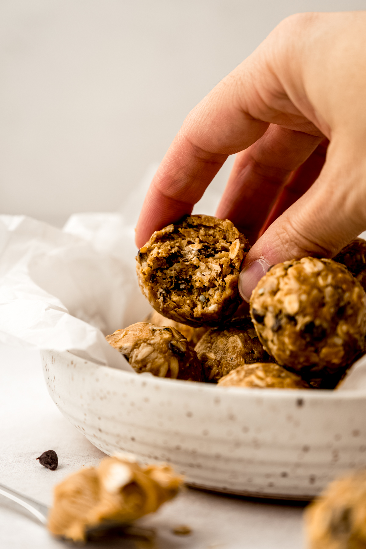 Someone is holding a chocolate chip oat bite that has a bite taken out of it.