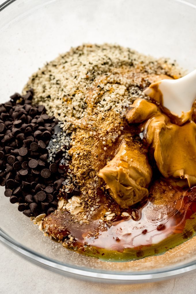 A bowl of the ingredients for chocolate chip oat bites with a spatula in it.