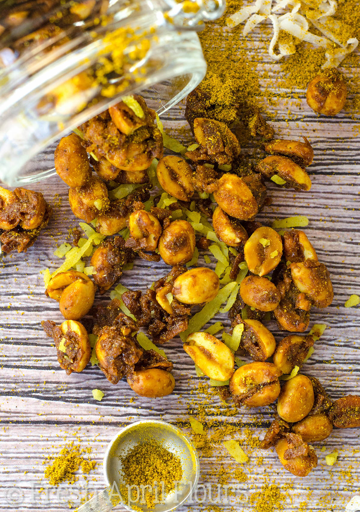 Aerial photo of toasted coconut curry peanuts on a surface.