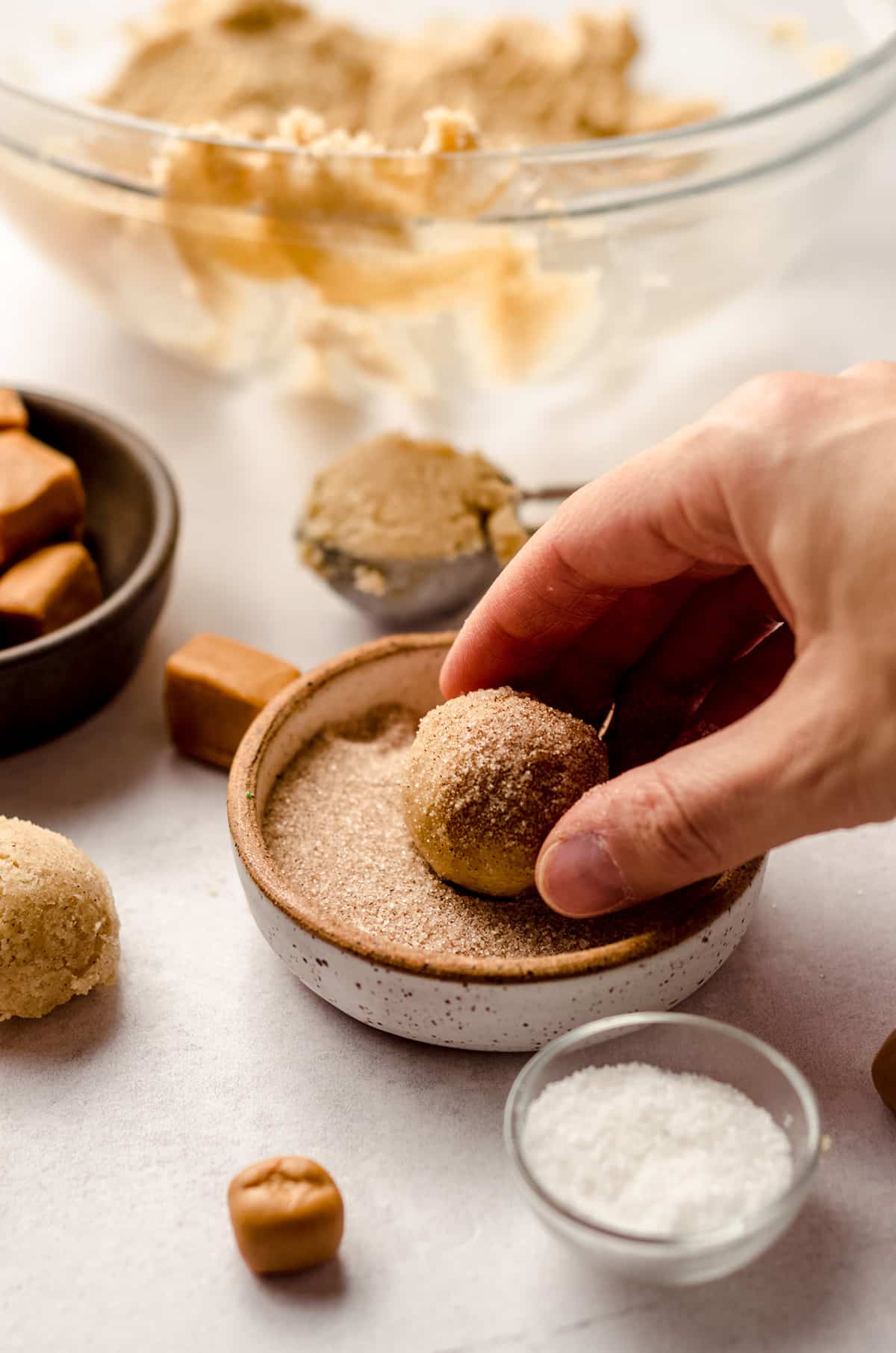 rolling caramel snickerdoodle dough into cinnamon sugar coating