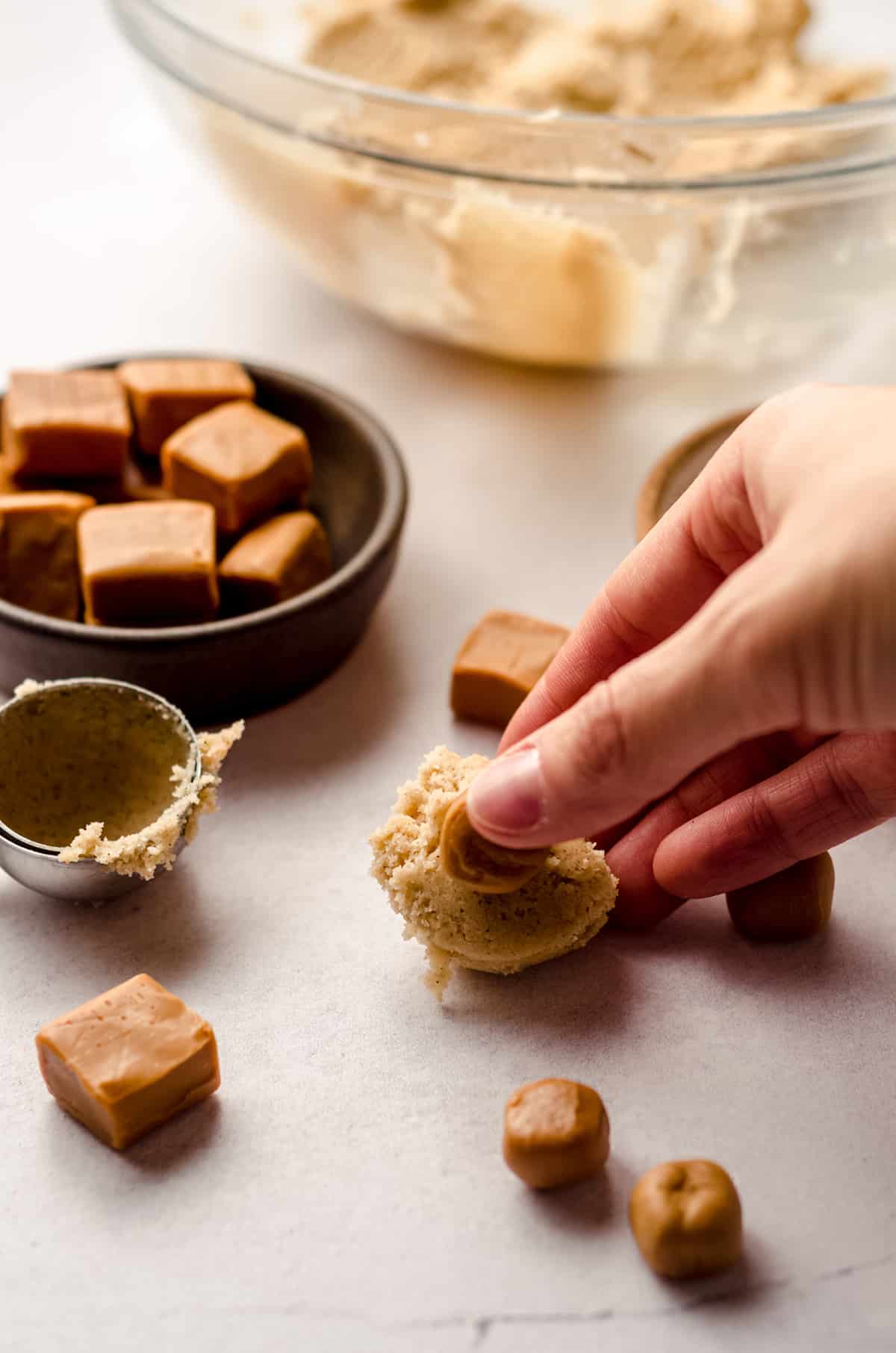 pressing a caramel into snickerdoodle cookie dough