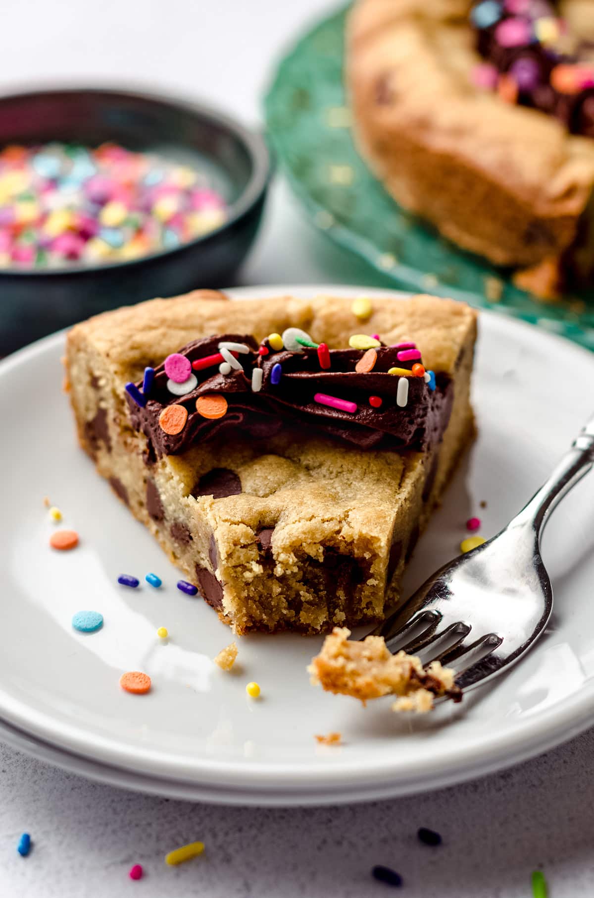 slice of chocolate chip cookie cake on a plate with a bite taken out of it