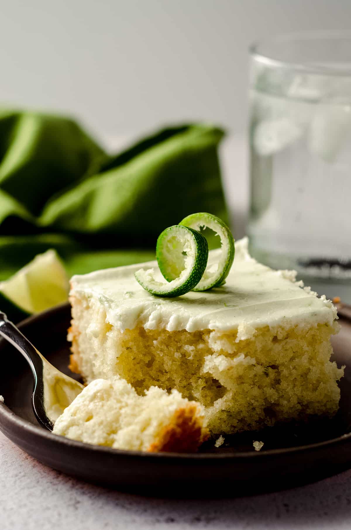 slice of gin and tonic cake sitting on a plate with a fork and a bite taken out of it