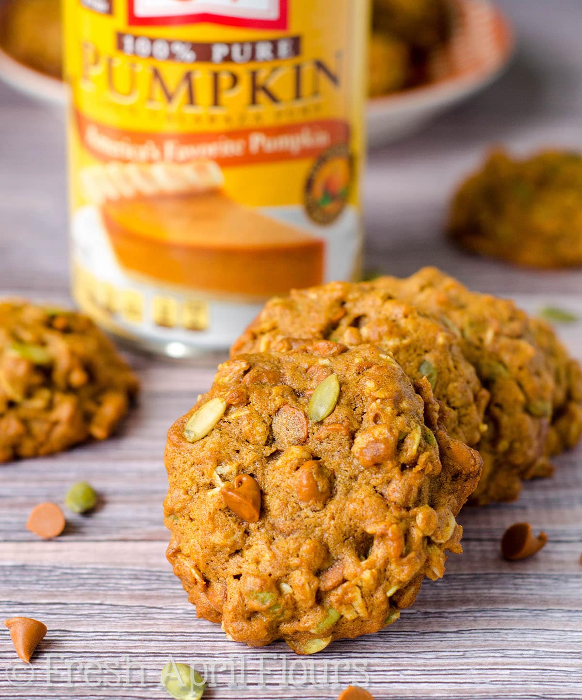 Pumpkin oatmeal cookies on a surface with a can of pumpkin in the background.