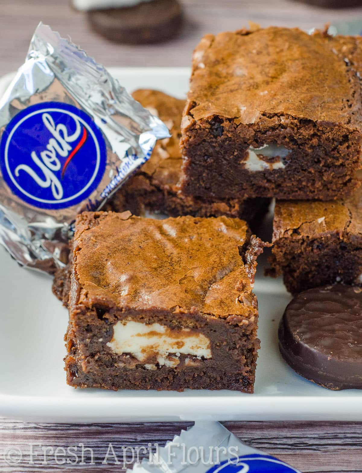 Peppermint Pattie stuffed brownies on a plate with Peppermint Patties around them.