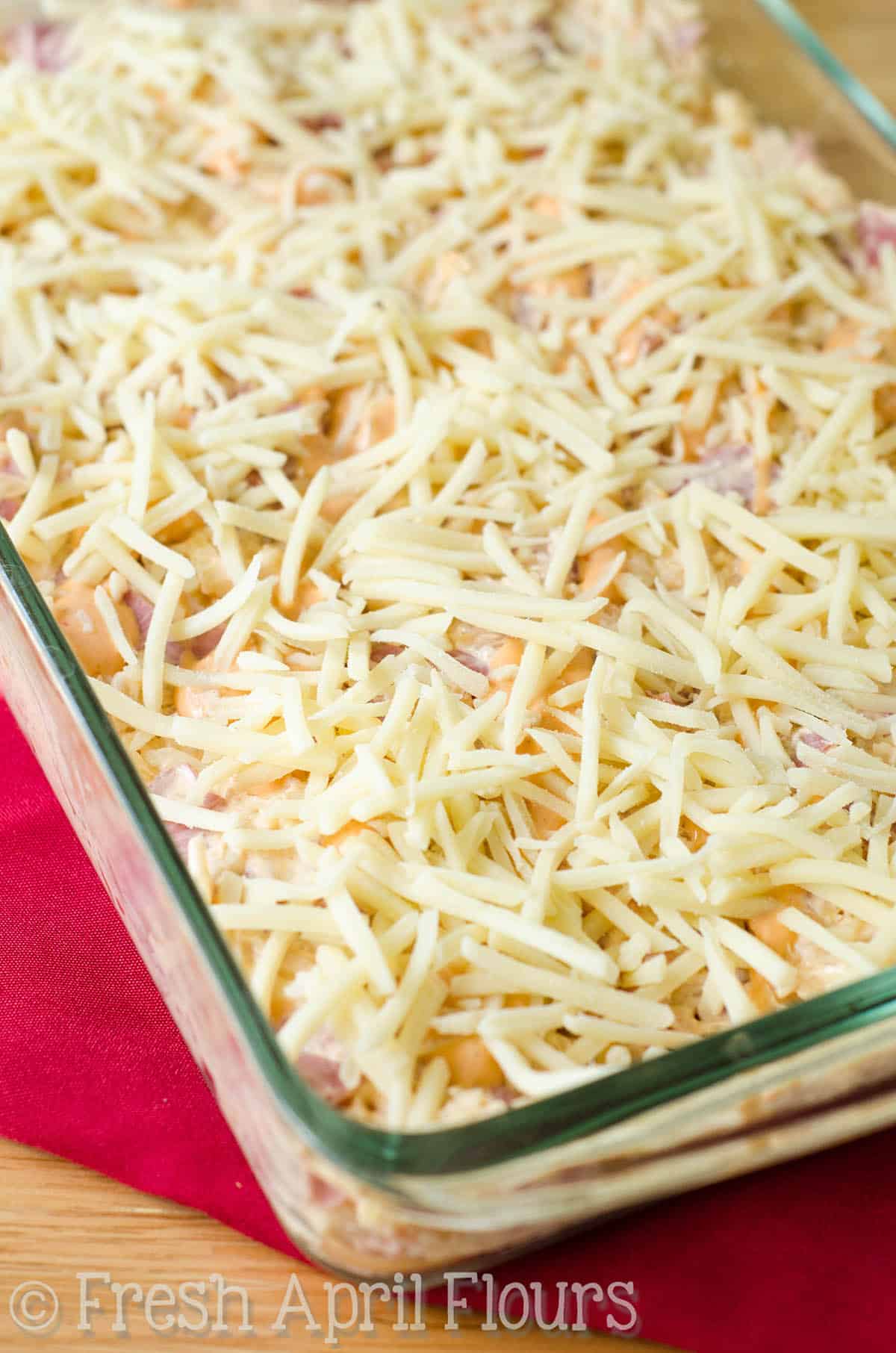 Shredded cheese on top of Reuben dip ready to be baked.
