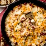 Aerial photo of a skillet of Reuben dip with a piece of marbled rye bread in it.
