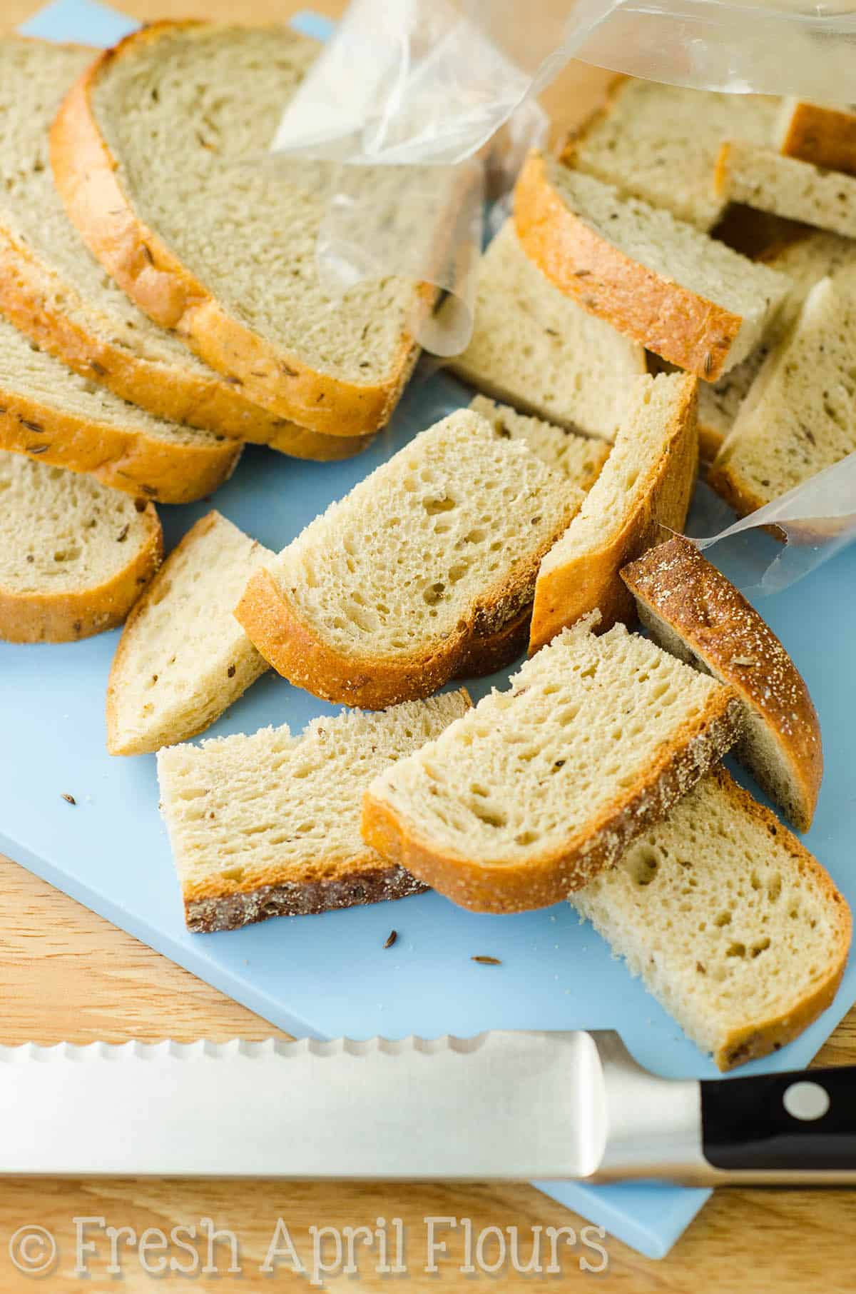 Sliced rye bread on a cutting board with a knife.