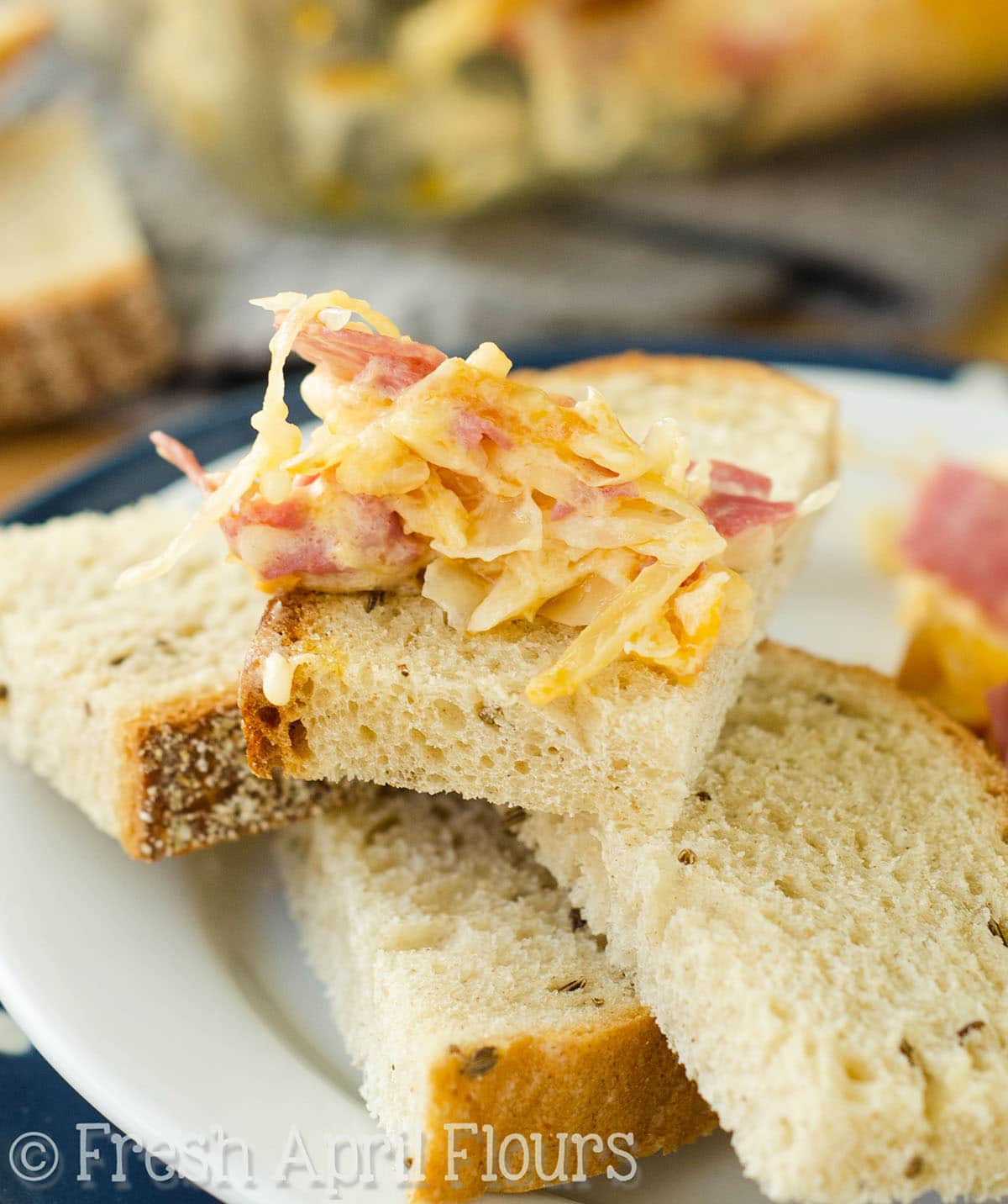 A stack of piece of bread with Reuben dip on one of the pieces.