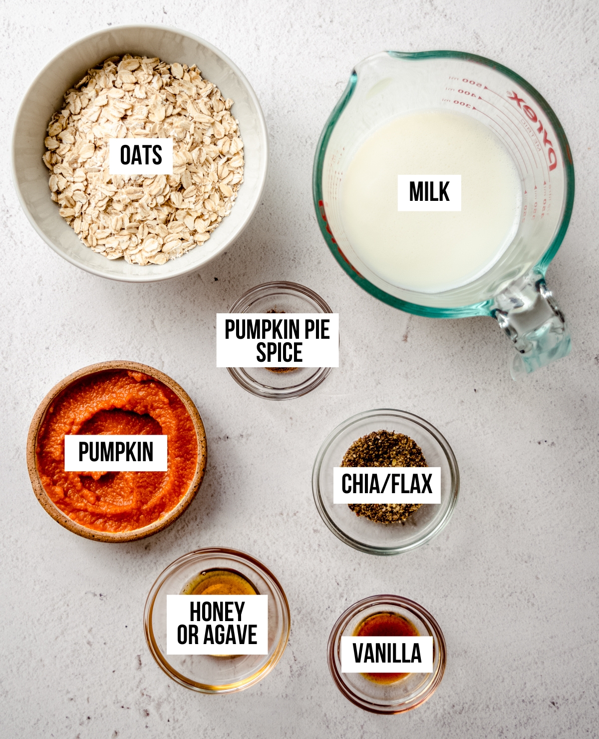 Aerial photo of ingredients to make pumpkin overnight oats with text overlay labeling each ingredient.