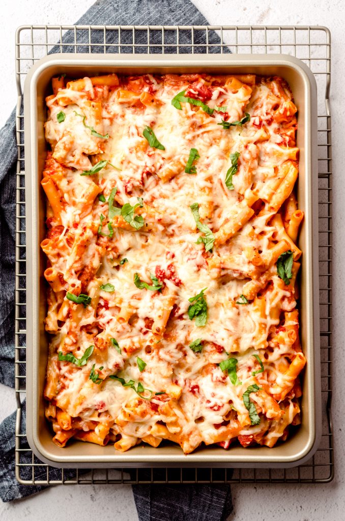 Aerial photo of baked ziti in a casserole dish topped with shredded basil.