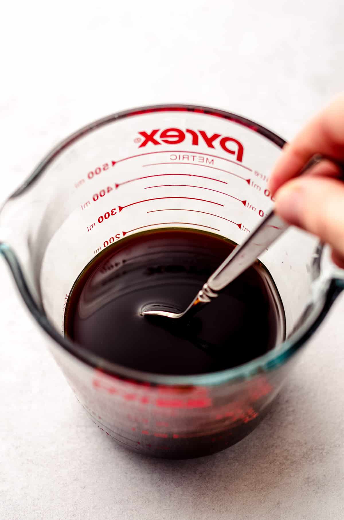 bloomed molasses with hot water in a measuring cup being stirred with a spoon