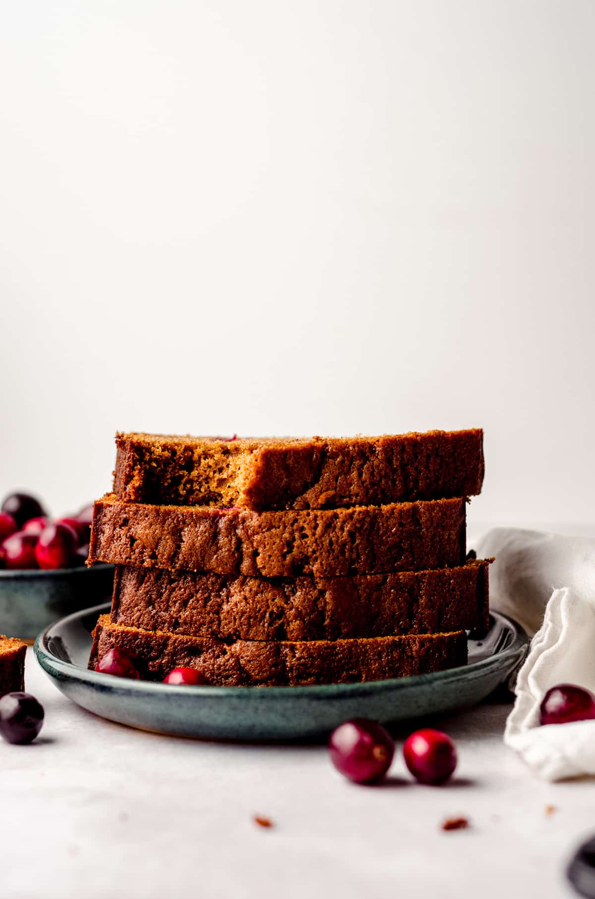 a stack of slices of cranberry gingerbread with a bite taken out of the slice on top
