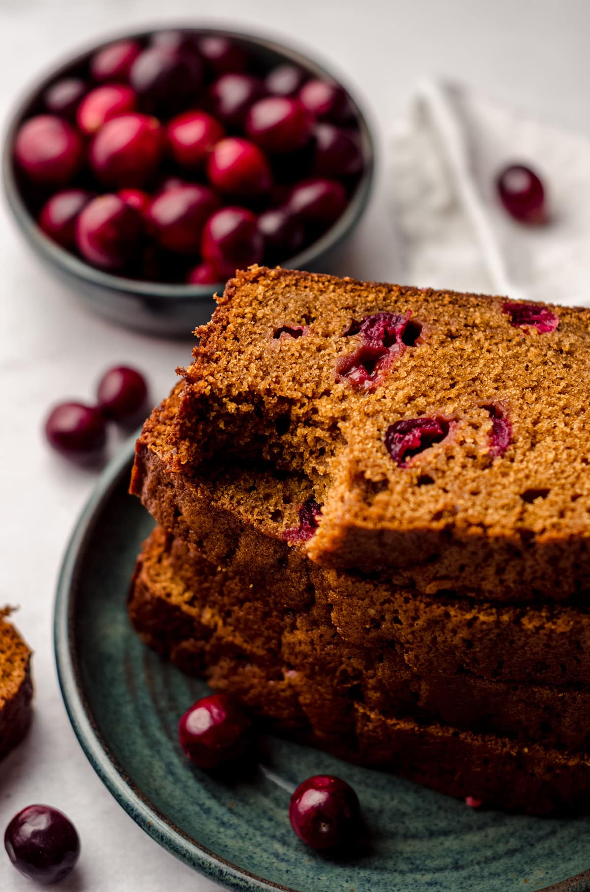 a stack of slices of cranberry gingerbread with a bite taken out of the slice on top