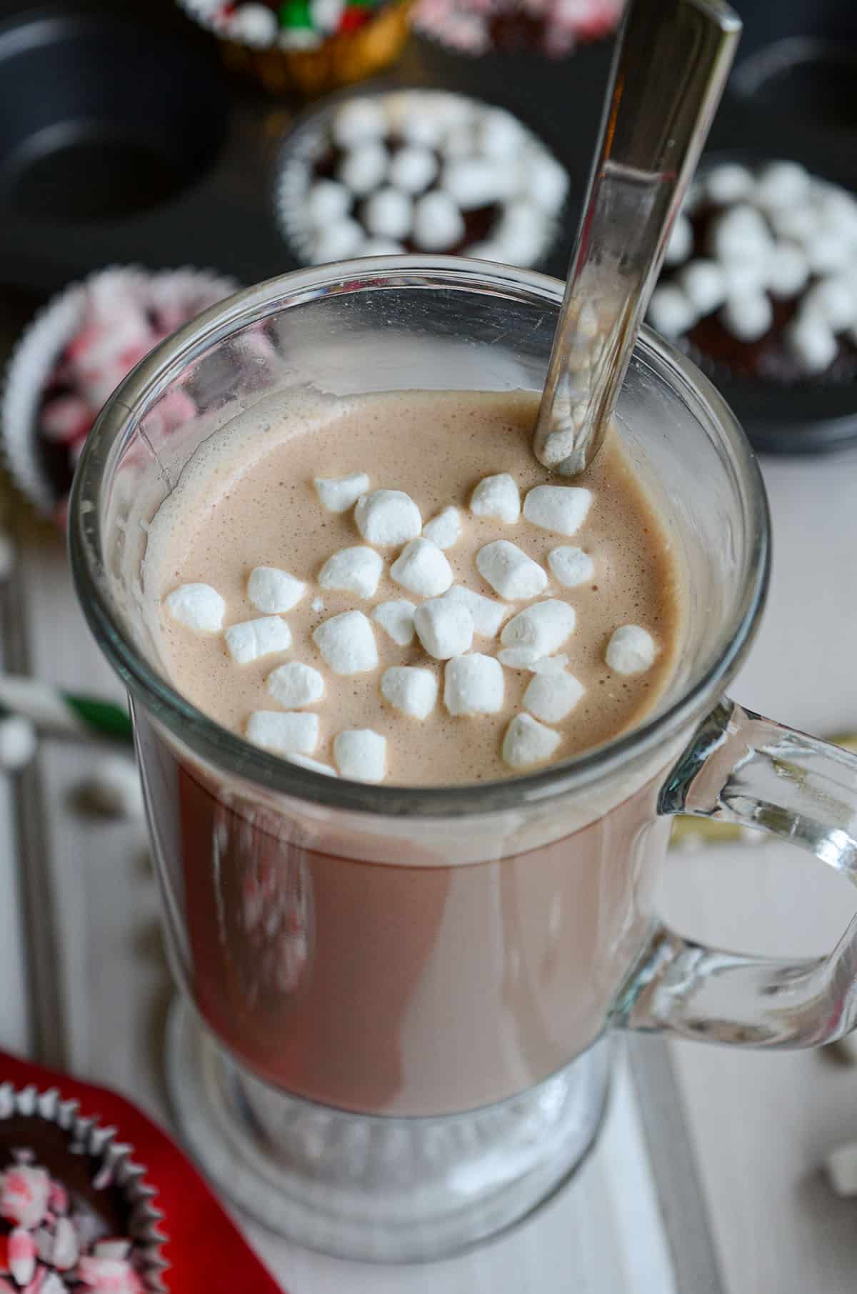 hot chocolate in a mug with a spoon and little mini marshmallows floating on top