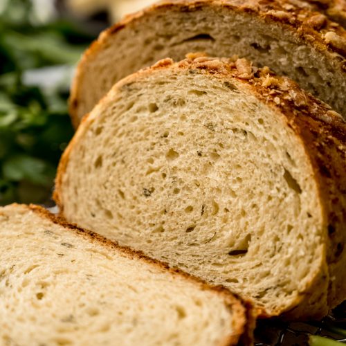 A sliced loaf of Parmesan parsley bread on a surface.