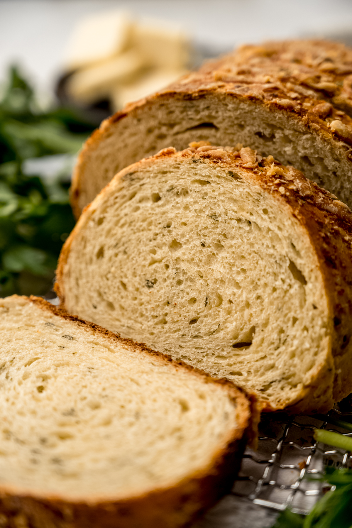 A sliced loaf of Parmesan parsley bread on a surface.