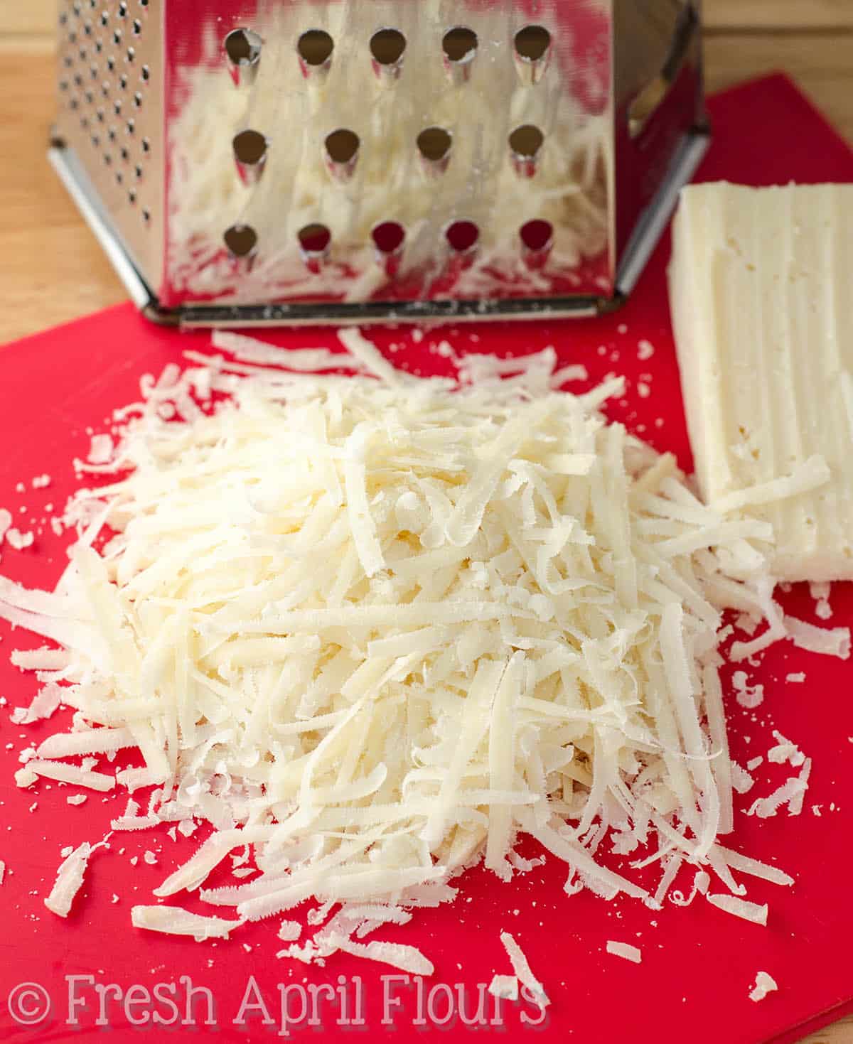 Shredded parmesan cheese on a cutting board.