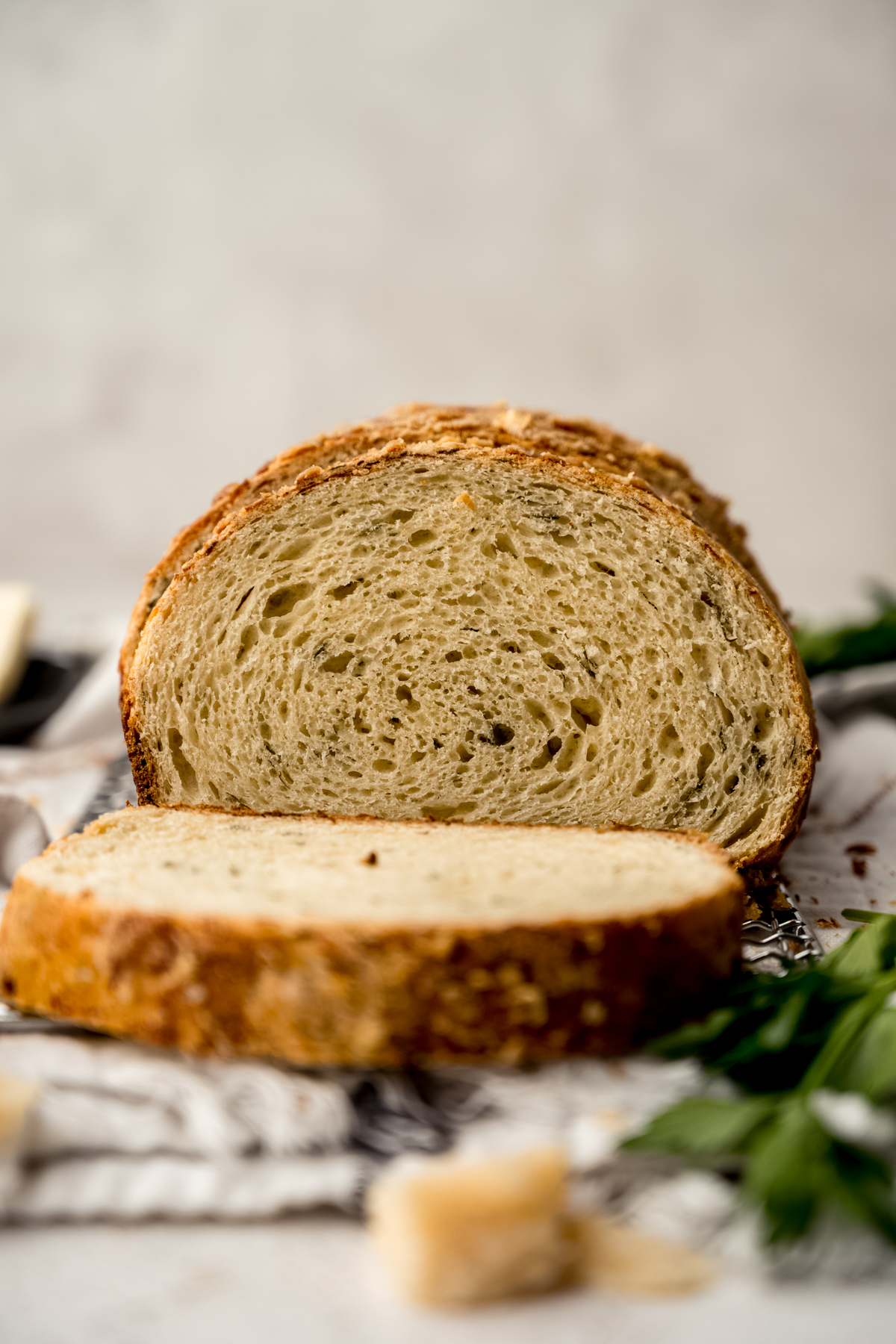 A sliced loaf of Parmesan parsley bread on a surface.
