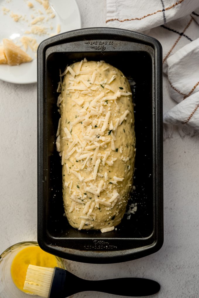 Aerial photo of a loaf of Parmesan parsley bread in a loaf pan after rising.