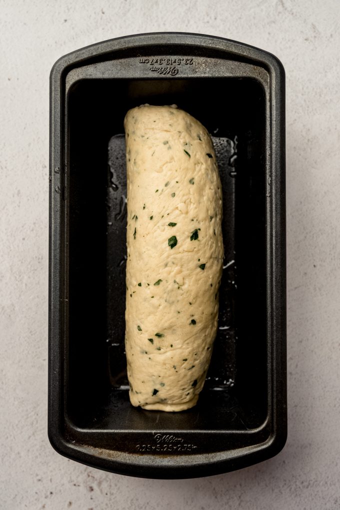Aerial photo of a loaf of Parmesan parsley bread in a loaf pan before rising.