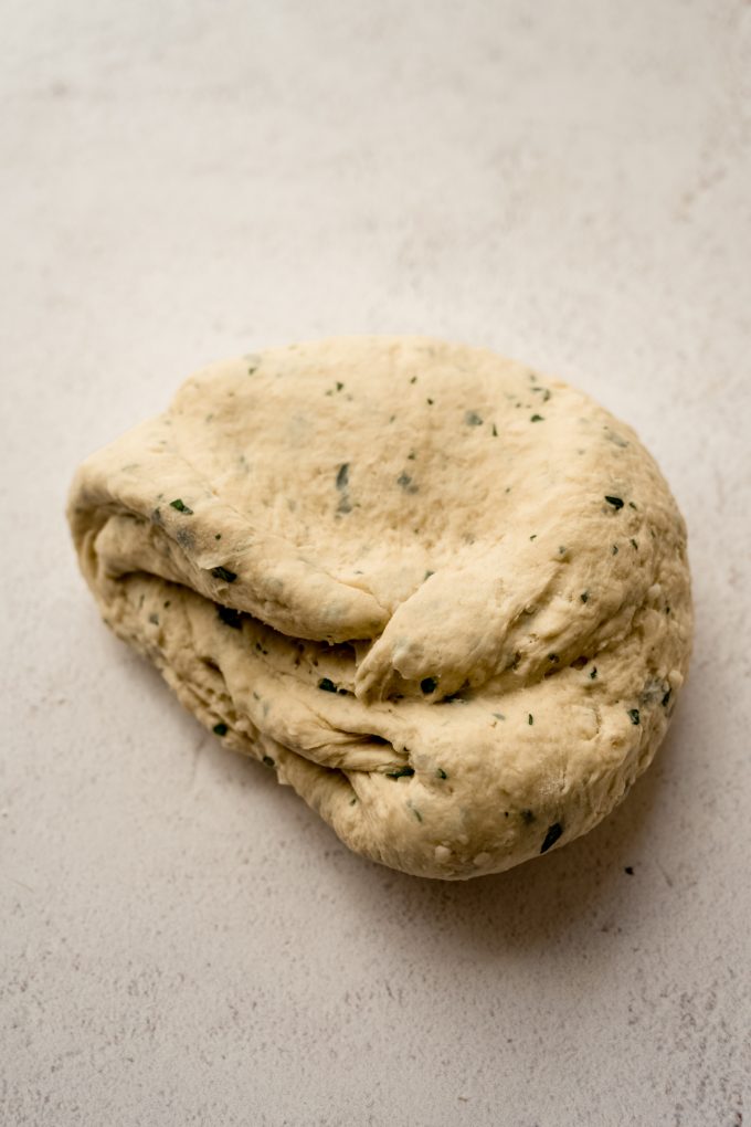 Parmesan parsley bread dough on a surface.