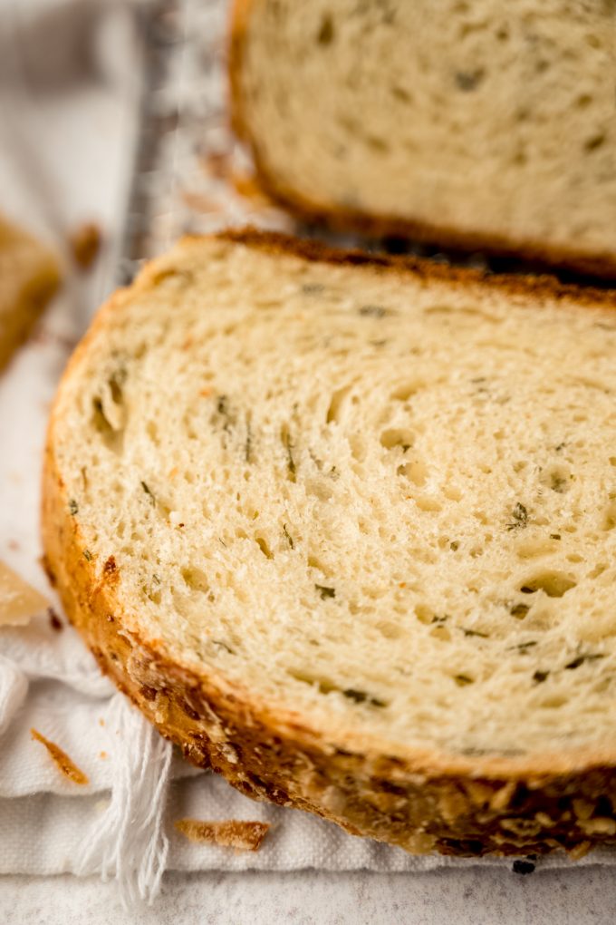 A sliced loaf of Parmesan parsley bread on a surface.
