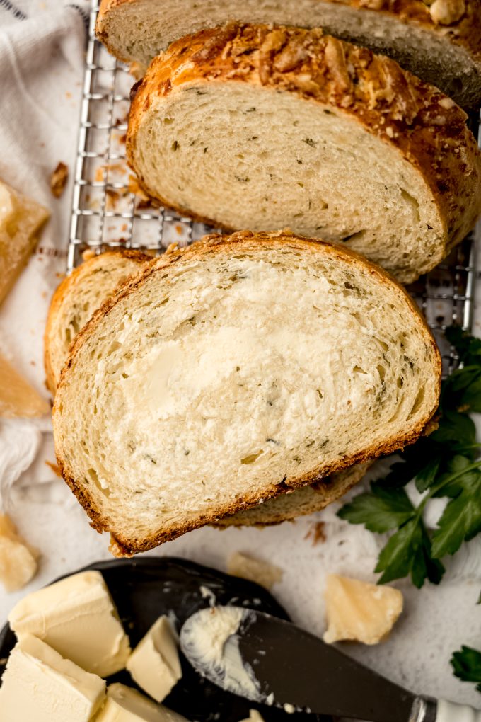 A slice of Parmesan parsley bread with butter on it.