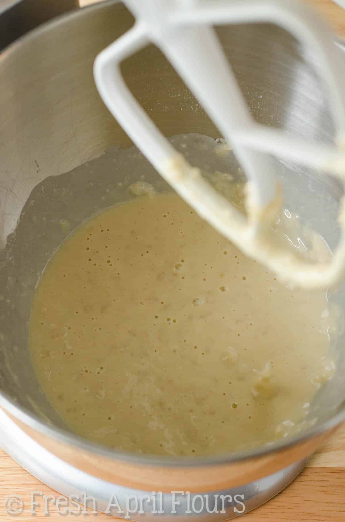 The start of dough for parmesan parsley bread in the bowl of a stand mixer.