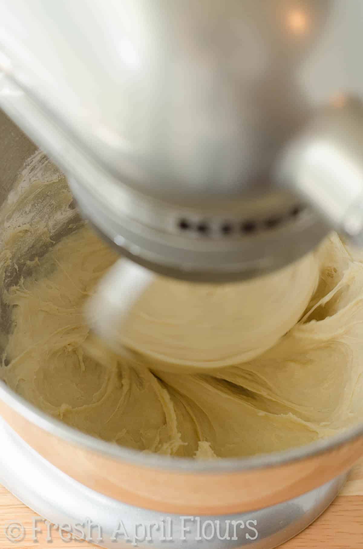 Bread dough in the bowl of a moving stand mixer.