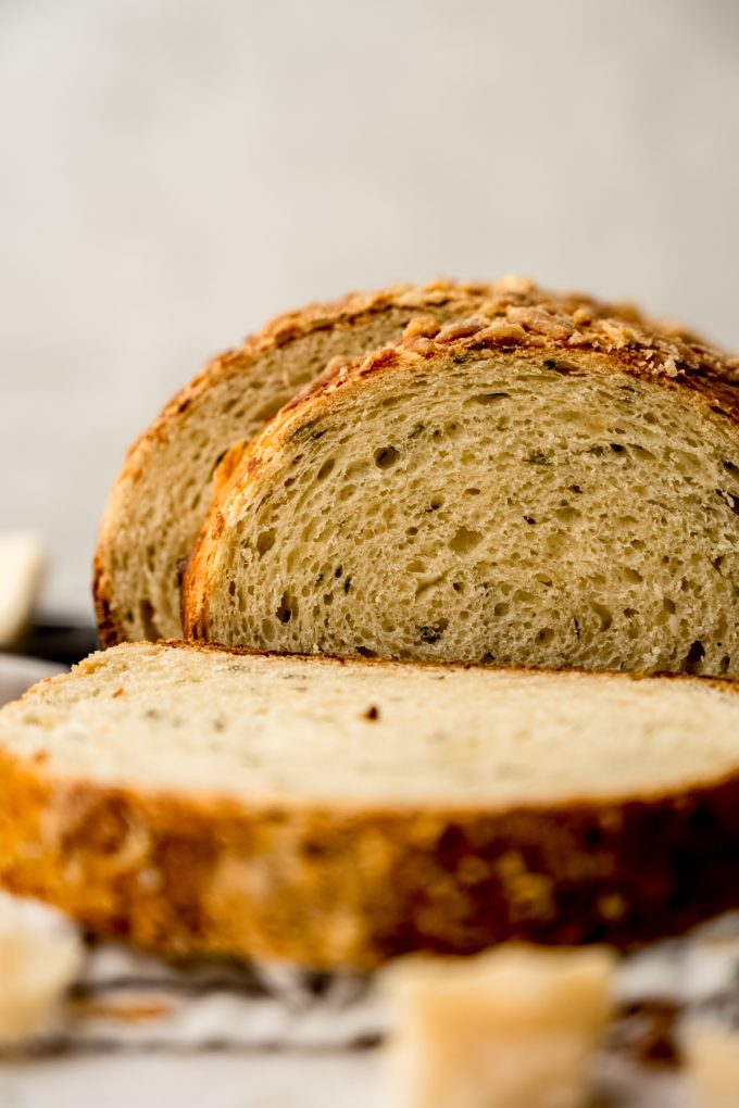 A sliced loaf of Parmesan parsley bread on a surface.