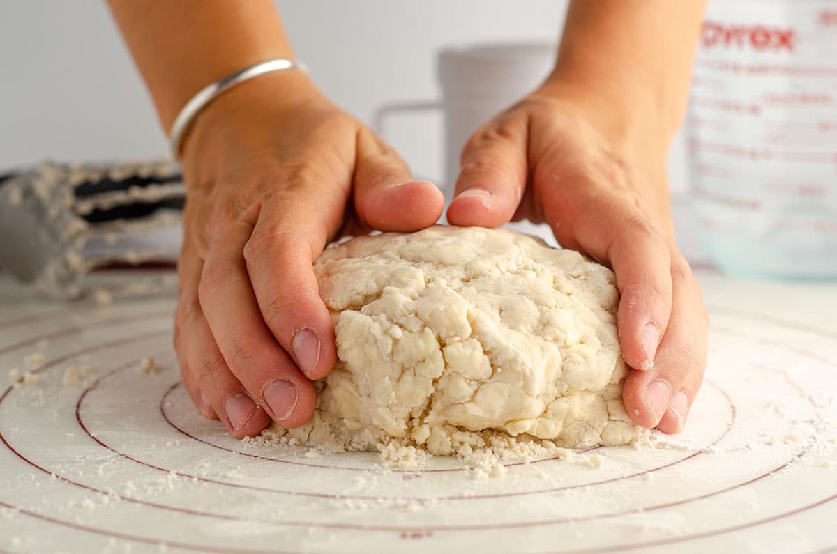 hands shaping pie dough on a pastry mat