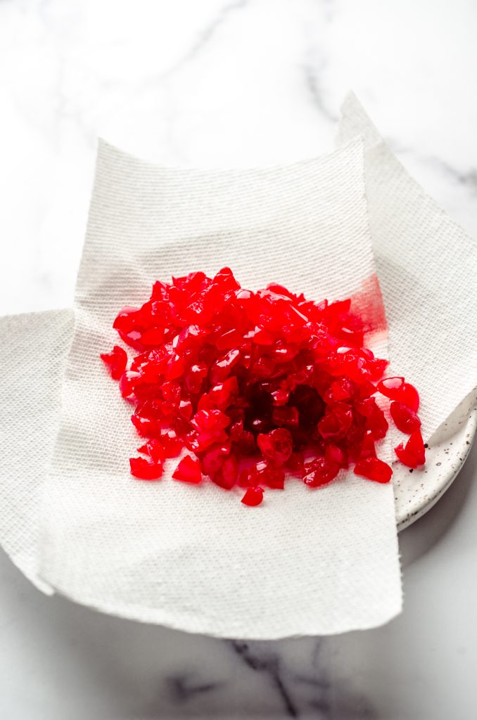 Chopped maraschino cherries on a paper towel ready to be squeezed dry.
