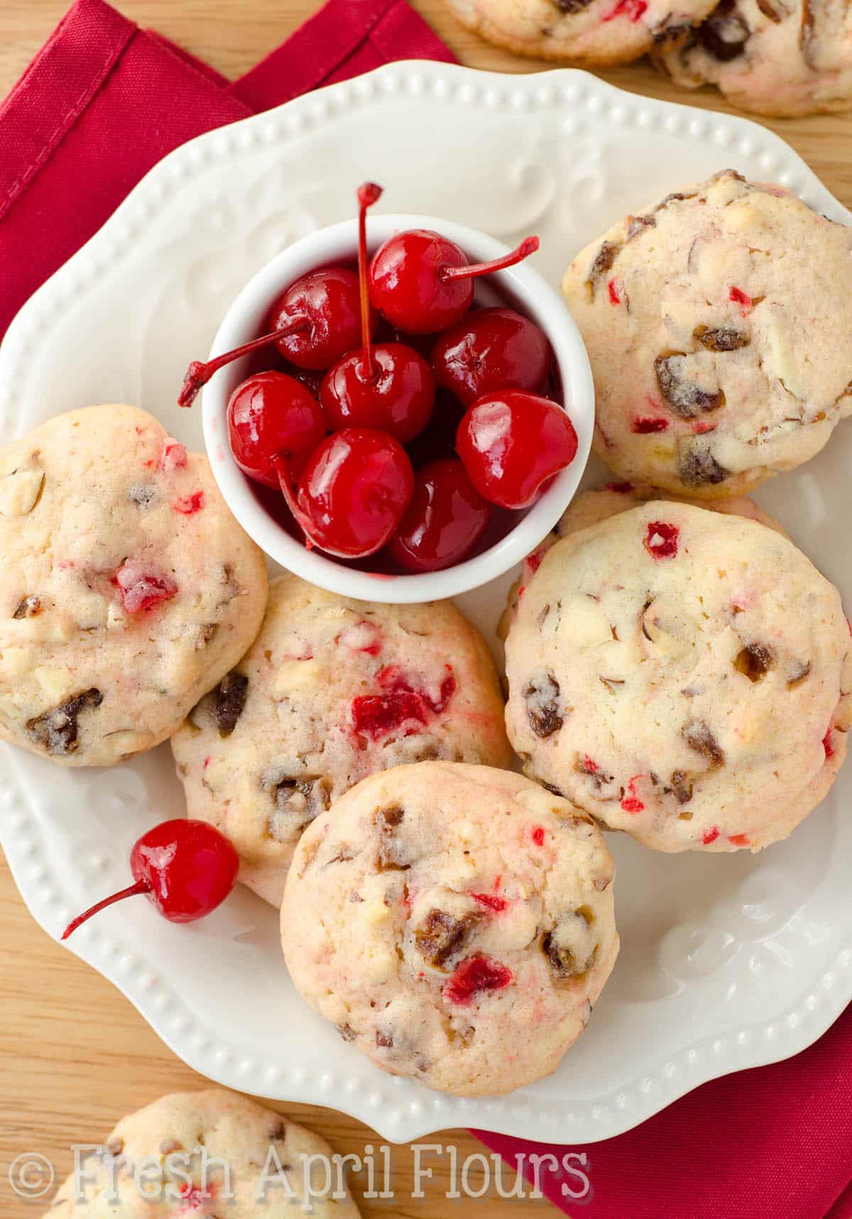 Aerial photo of cherry almond date cookies with a small bowl of maraschino cherries.