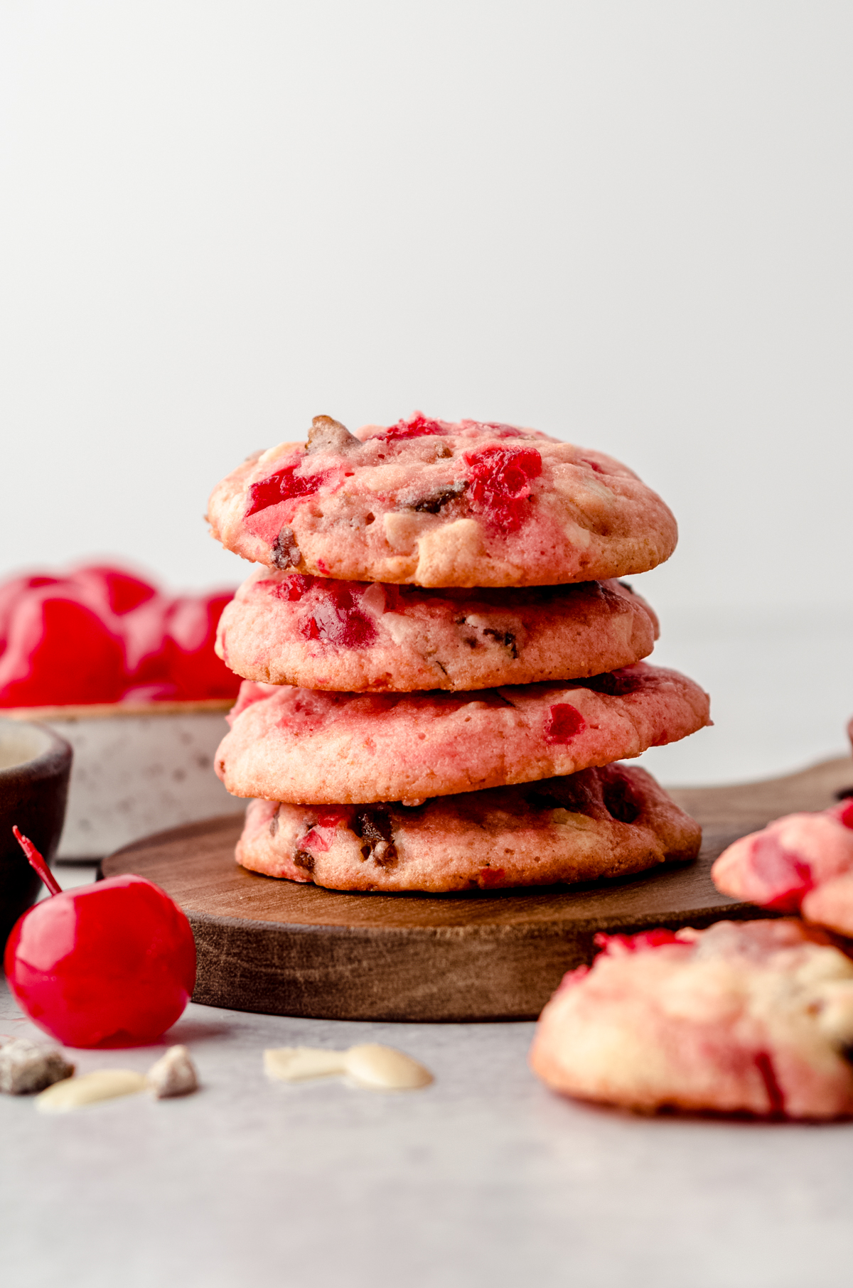 A stack of cherry almond cookies with dates. There are maraschino cherries around it.