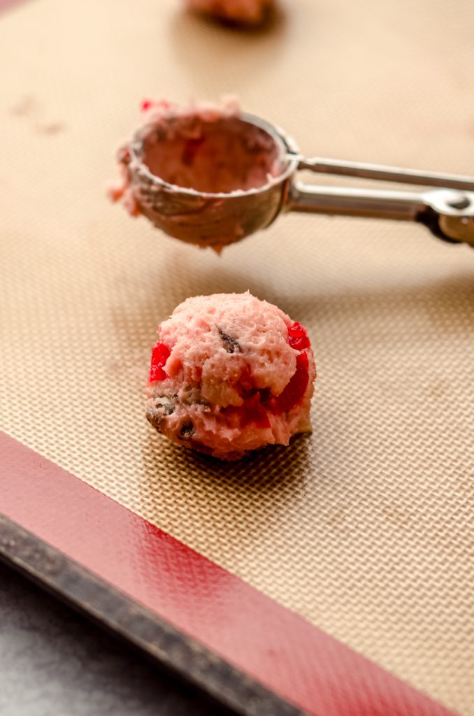 Cherry almond date cookie dough ball on a baking sheet.