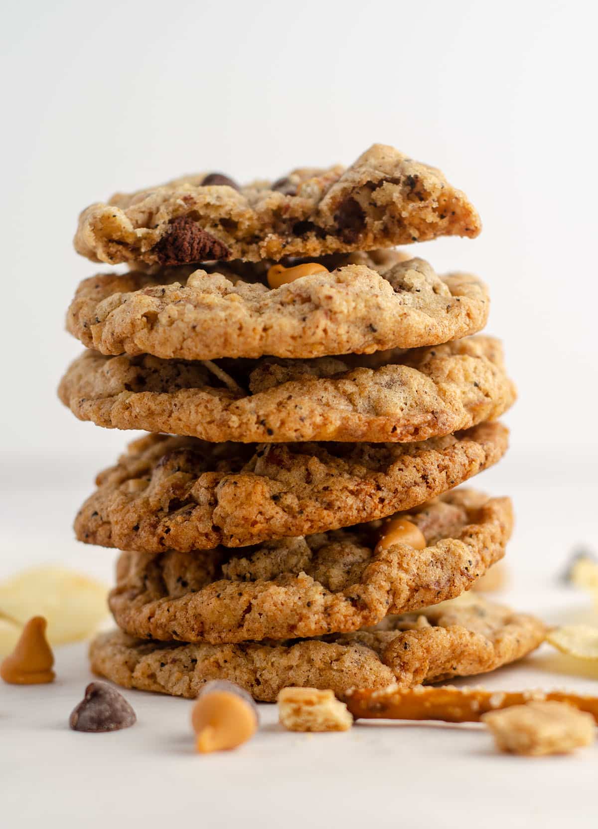stack of compost cookies scattered with chips, pretzel pieces, chocolate chips, and butterscotch chips