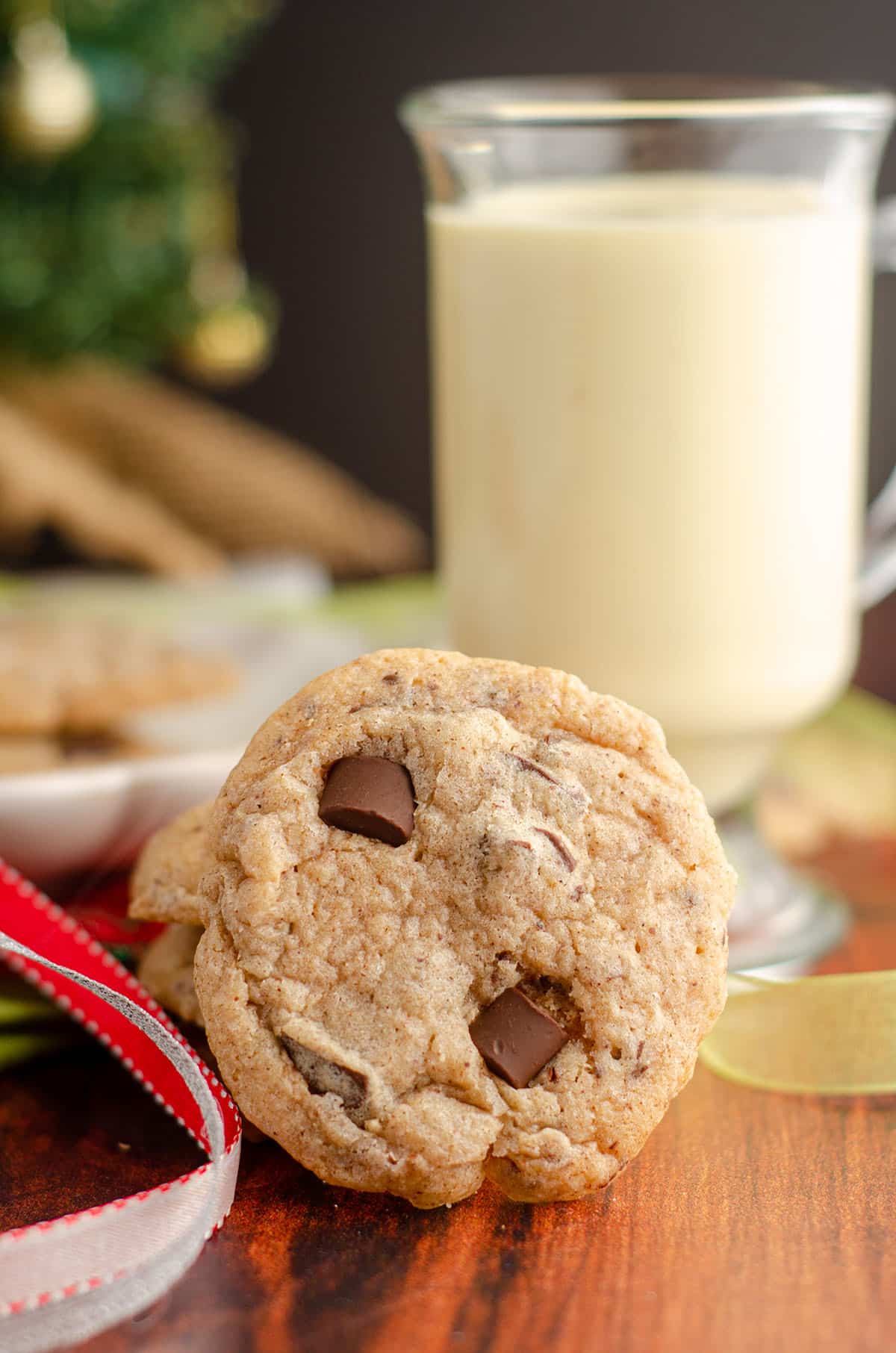 eggnog chocolate chunk cookie sitting with christmas ribbons and eggnog