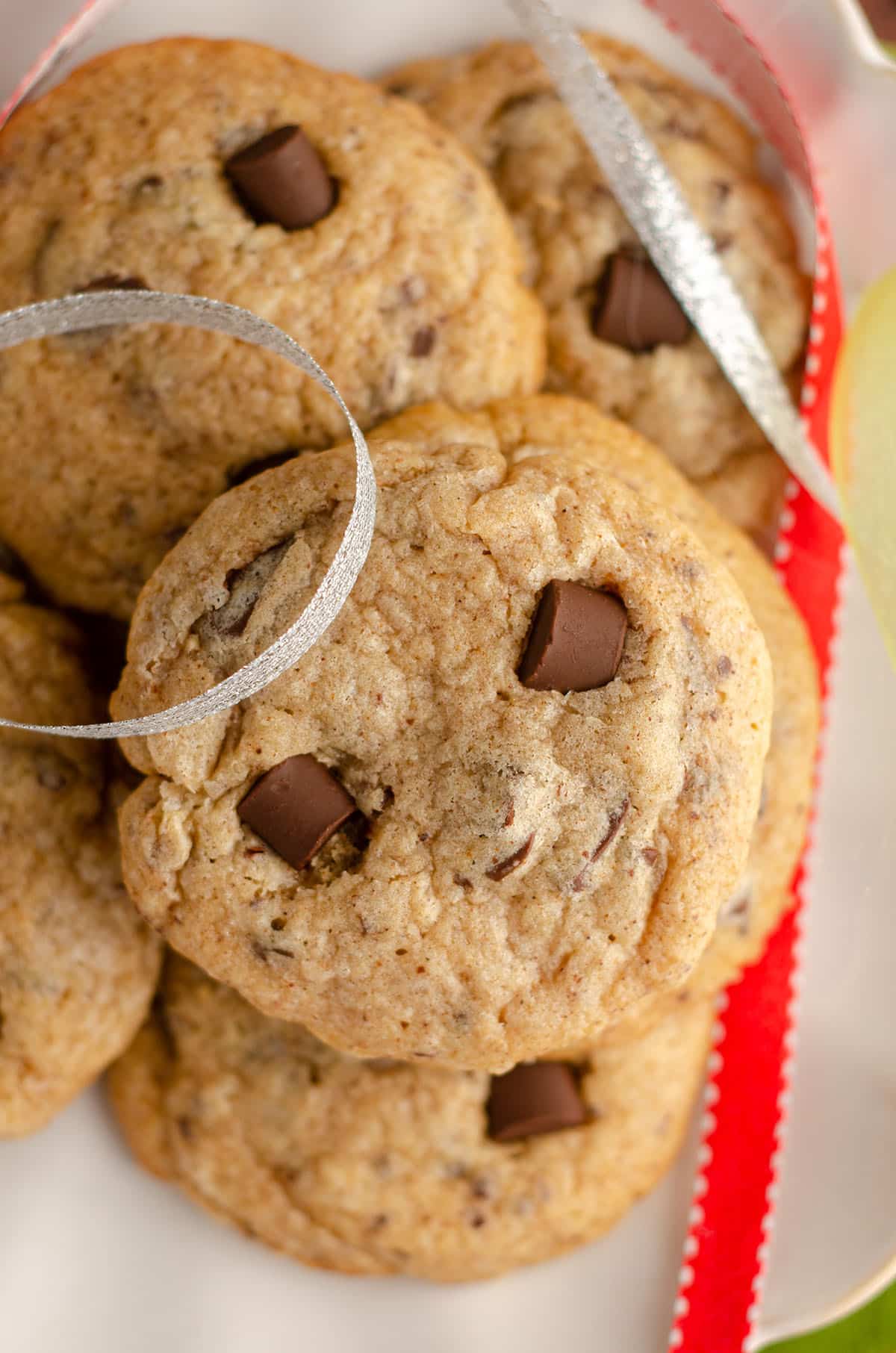 aerial photo of eggnog chocolate chunk cookie on a plate with silver and red ribbons around it